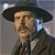 Pixelated portrait of a person wearing a wide-brimmed dark hat and dark jacket with light collar, set against a muted gray background with light blue and white highlights.