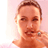 Pixelated static image of a person's face and upper shoulders with light brown hair, closed eyes, and visible facial features against a pale pink background.