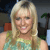 A pixelated image of a person with long blonde hair wearing a light green sleeveless top, smiling with eyes partially closed against a blurred background.