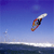 Pixelated static image of a windsurfing board with sail against blue sky and water background.