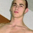 Pixelated close-up of a person with short brown hair, light skin tone, and closed eyes against a pale background.