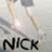 Pixelated image with light gray background, abstract shapes in beige and white tones, and bold black text reading "NICK" at the bottom.