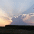 A landscape scene with a mountain silhouette under a sky transitioning from light blue to orange, featuring clouds and subtle ground details.