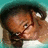 Two people in a close embrace, one with dark curly hair and glasses kissing another person's cheek against a teal background.