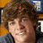 A person with brown curly hair and a dark gray hoodie appears in three with pink text overlays reading 'i', 'love', and 'SHECKLER!' against a blurred background
