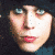 A pixelated image of a person with dark hair and blue eyes, next to a black pentagram symbol on white background.