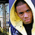 Pixelated static image of a person with dark hair and light skin wearing a blue and white top, positioned against a blurred background with vertical elements.