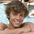 Pixelated image of a person with brown curly hair lying on a light blue background with white patterns, next to text reading 'ryan sheckler is bangable <3'.