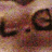 Pixelated static image with indistinct shapes in warm brown, pink, and beige tones, no clear subjects or text visible.