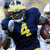 Pixelated image of a football player in dark blue uniform with yellow number 4, holding a brown football, next to text reading MINOR 4 HEISMAN on dark blue background.