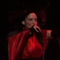 A woman in a red satin outfit sings into a microphone across showing varied hand and head positions