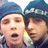Two individuals wearing dark blue knit hats with white text, positioned side-by-side in a
