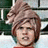 Pixelated static image of a person with light brown hair styled in an updo, wearing red clothing against a blurred background.