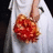 A pixelated image shows a person in a white shirt holding a large red and orange object resembling a brain or abstract shape.
