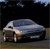 Pixelated image of a silver sedan with headlights on, positioned on a road under a dark sky with faint clouds.