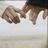 Pixelated image of hands clasped over a light surface with cyan text on black background reading 'nate never let go of me!'