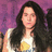 A static pixelated image shows a person with long dark hair wearing a white top and yellow patterned garment against a purple background.