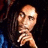 A pixelated image of a person with long dark hair resting their chin on one hand, set against green background text repeating 'Is this love' and 'I wanna know'.