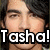 A pixelated image of a person with dark hair and light skin, featuring bold text overlay reading "Tasha! Tasha!" in white letters with black outlines.