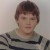 Static pixelated image of a person with short brown hair wearing a striped shirt against a light background.