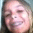 Pixelated close-up of a smiling person with light skin and dark hair, wearing a dark top against a blurred background.