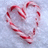 A heart-shaped arrangement of red and white striped candy canes on a light blue pixelated background.