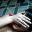 A hand with red-painted nails rests on a blue patterned fabric background, fingers slightly curled in three