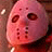 Pixelated pink mask with dark eye holes and mouth cutouts on a brown background, appearing as a static single-frame image.