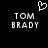 Black background with white pixelated text 'TOM BRADY' in two identical vertical and a small heart symbol above the left