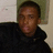 Pixelated static image of a person in dark clothing against a light background with greenish tones.