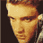 Pixelated close-up of a person's face with brown hair and light skin tones rendered in warm yellow-orange hues against dark background.