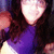 Pixelated image of a figure with long dark hair wearing purple clothing, holding a bright glowing object against a dark background.
