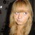 A pixelated image shows a person with long blonde hair and glasses on the left, while the right side displays a white heart icon on bright pink background.