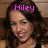 Pixelated portrait of a person with long dark hair and a black top, overlaid with pink text reading 'Miley' at the top.