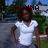 Pixelated image of a person in a white shirt with 'SHAUNA' text overlaid in red, standing outdoors with greenery and a building in the background.