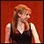 A woman with long light brown hair in a black sleeveless top against a solid red background, shown in two sequential poses.