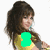 A woman with long brown hair and bangs wears a yellow top, holding a microphone; text overlays change across frames.