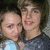 Two people in close proximity, one wearing a light blue top and the other dark clothing, with blurred background.