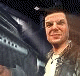 Animated contact sheet showing multiple frames of a person in a dark jacket and white shirt against a blurred background with repeated text overlays.
