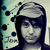 A person with dark hair and a hooded garment appears in a static image with a stylized background featuring black and blue dots and partial text.