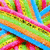 A colorful, pixelated pattern of interwoven pink, blue, green, and orange stripes with repeated text overlays in yellow, orange, and cyan backgrounds.