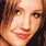 Pixelated close-up of a person with light brown hair, fair skin, and red lips smiling slightly against dark background.