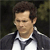 Pixelated image of a person with short brown hair wearing a dark jacket over a white collared shirt against a dark background.