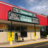 Static image of a building with red awnings and a teal sign under a blue sky.