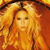A pixelated static image of a person with long flowing blonde hair against a warm-toned background of orange and yellow hues.