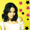 A person with shoulder-length dark hair wears a white off-shoulder top against a bright yellow background with scattered pink and black stars.