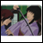 Pixelated anime-style image of two characters in a close embrace, one with dark hair in purple clothing, the other with brown hair in blue clothing, against a green background.