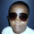 Pixelated close-up of a person wearing dark sunglasses and a white shirt against a blue background.