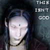 A static image of a person with long dark hair and a bindi, wearing a dark jacket over a light top against a textured gray background.