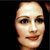 Pixelated close-up of a person's face with light skin tone, dark eyes, and brown hair against a black background.